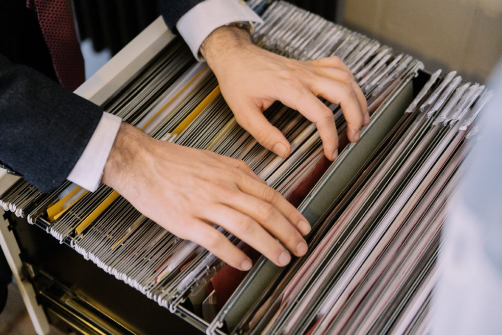 Hands searching through folders in a filing cabinet photographed in Stroud Green North London for Davies & Davies Estate Agents