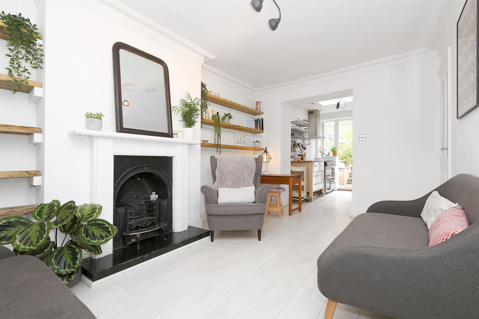 A photo of a open plan living room with a cast iron fire place and indoor plant.