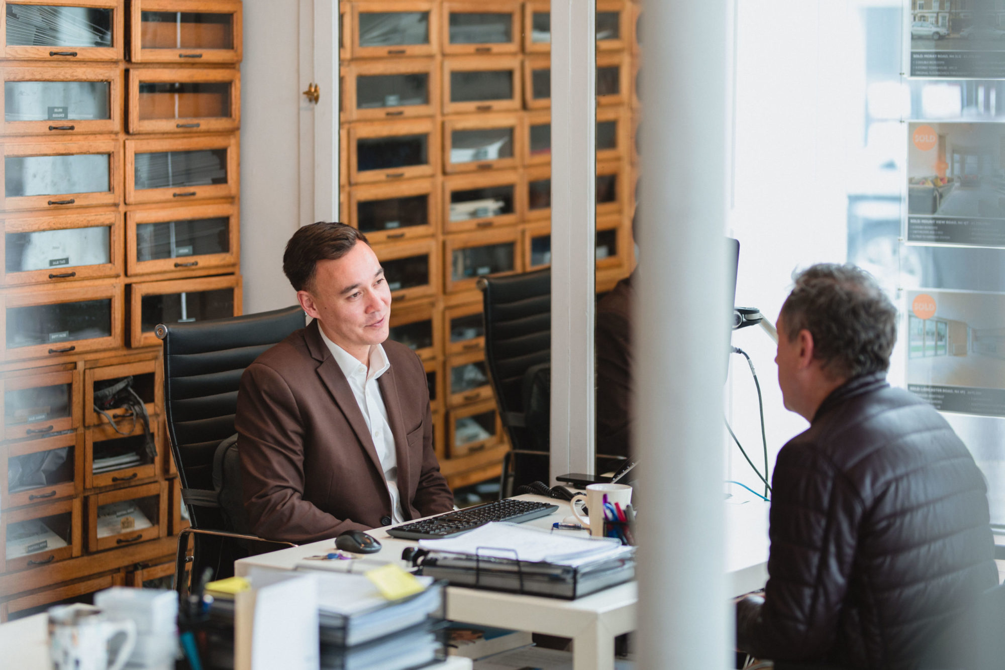 Davies & Davies team member behind at a desk providing professional experience to a client seated opposite him.