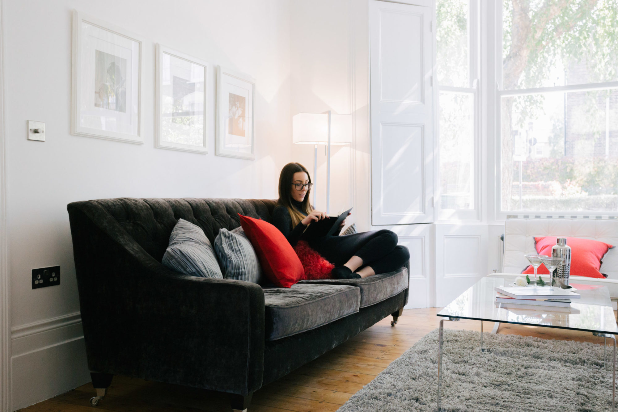 Photo of a woman sat on a sofa reading.