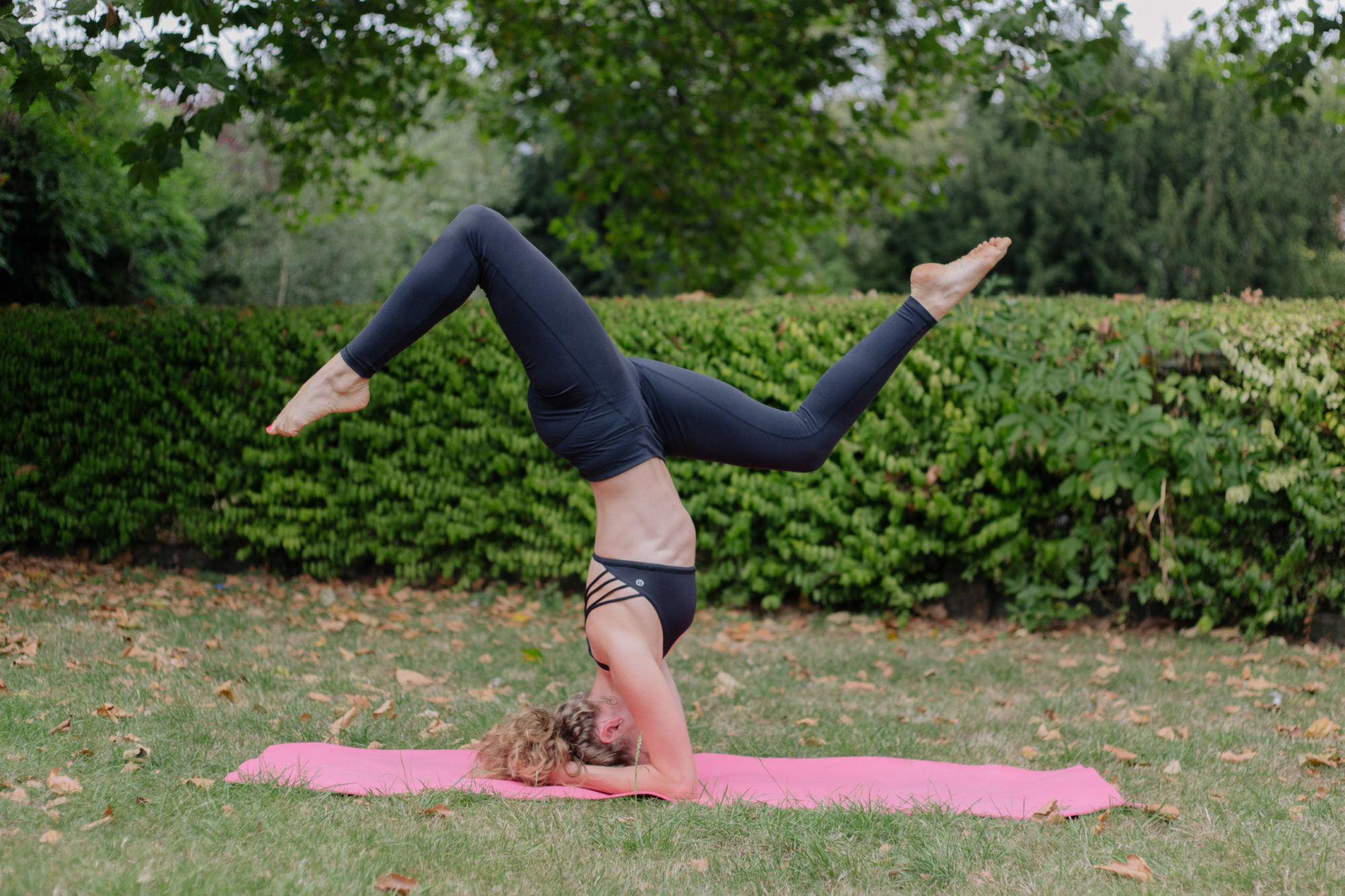 Woman doing yoga on a pink mat in the park