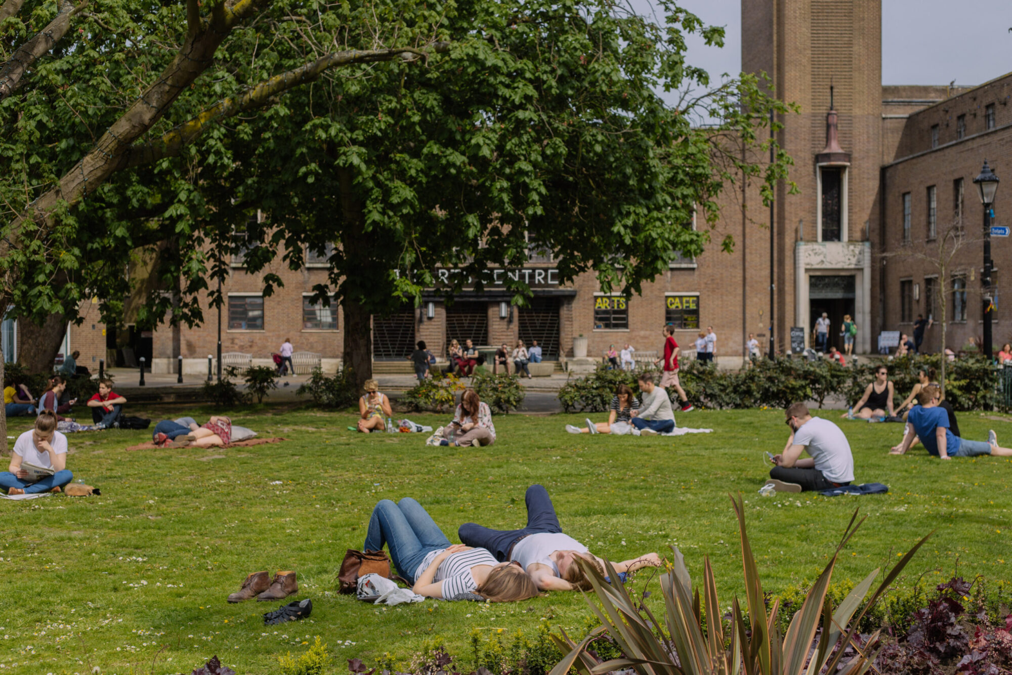 People sitting and lying on the grass of a local park in Crouch End.