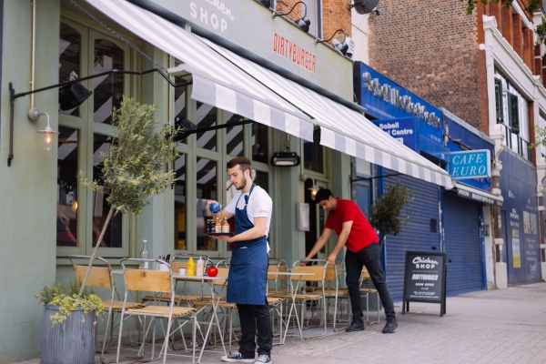 A waiter clearing the outside tables of a restaurant in Holloway.