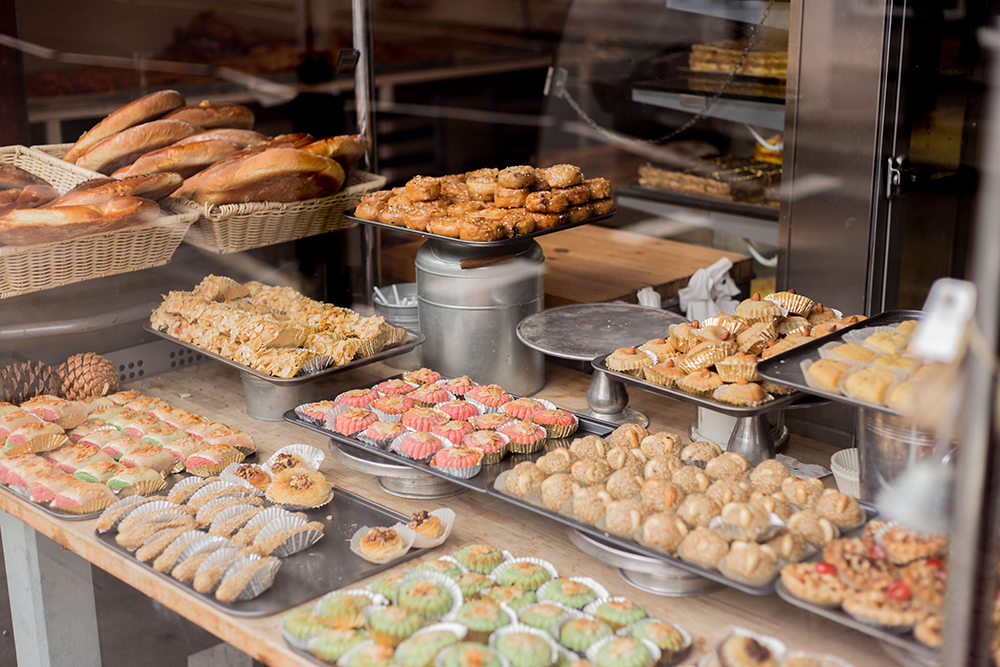 A window display of a local bakery on Finsbury Park presenting a colourful display of cakes, pastries and bread.