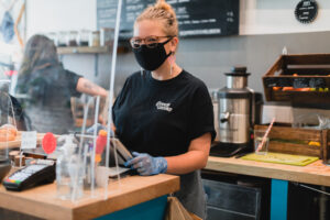 An employee of Common Ground wearing a mask at the till.