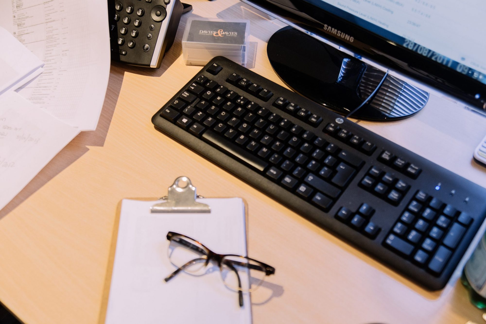 A picture of desk at Davies & Davies Estate Agents in Finsbury Park, with keyboard, monitor, notepad and glasses all in sight.