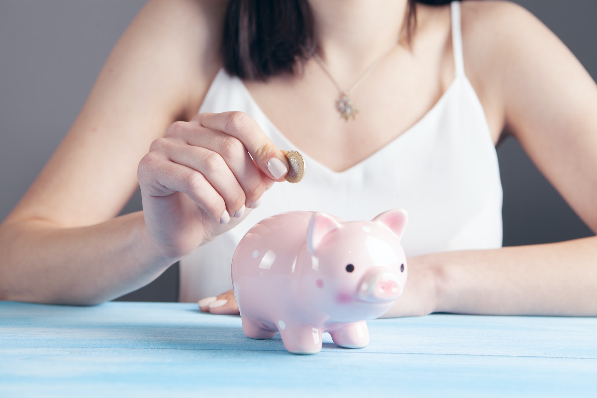 Photo of a woman putting coins into a piggy bank